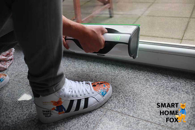 Man sieht, wie der Vorwerk Kobold VG100 am unteren Fensterrand leicht angehoben werden muss.